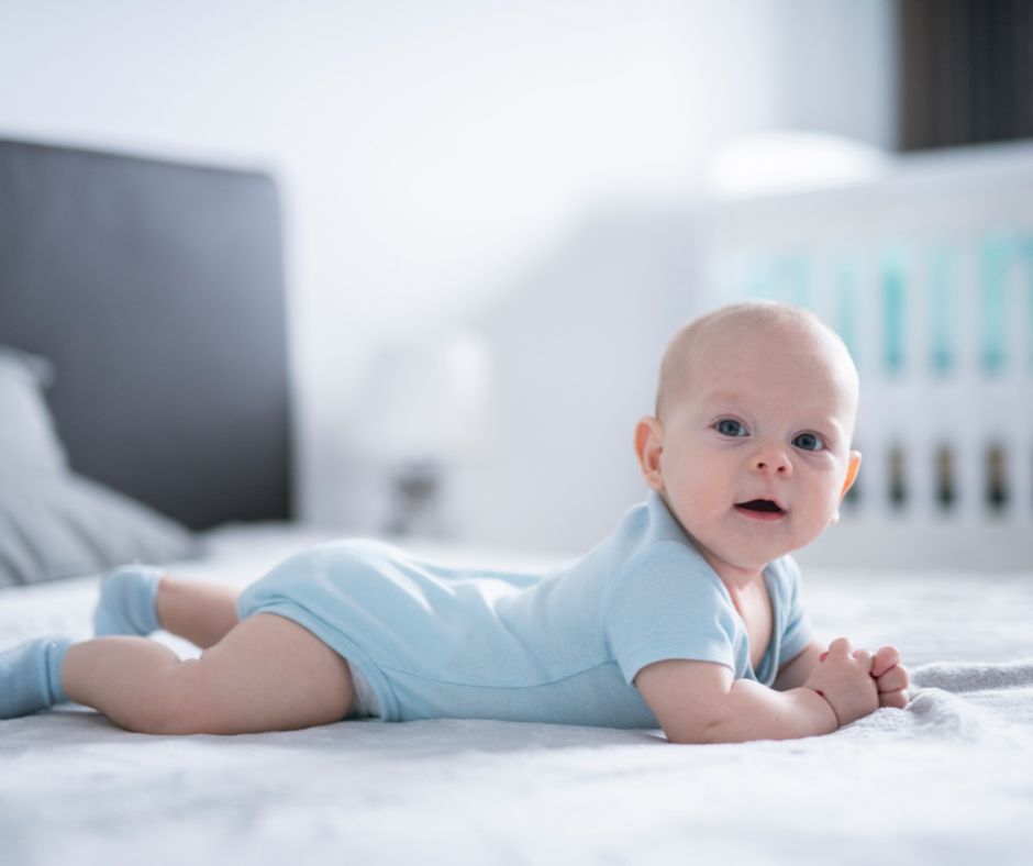 baby lying on his belly on the floor looking directly at camera curious