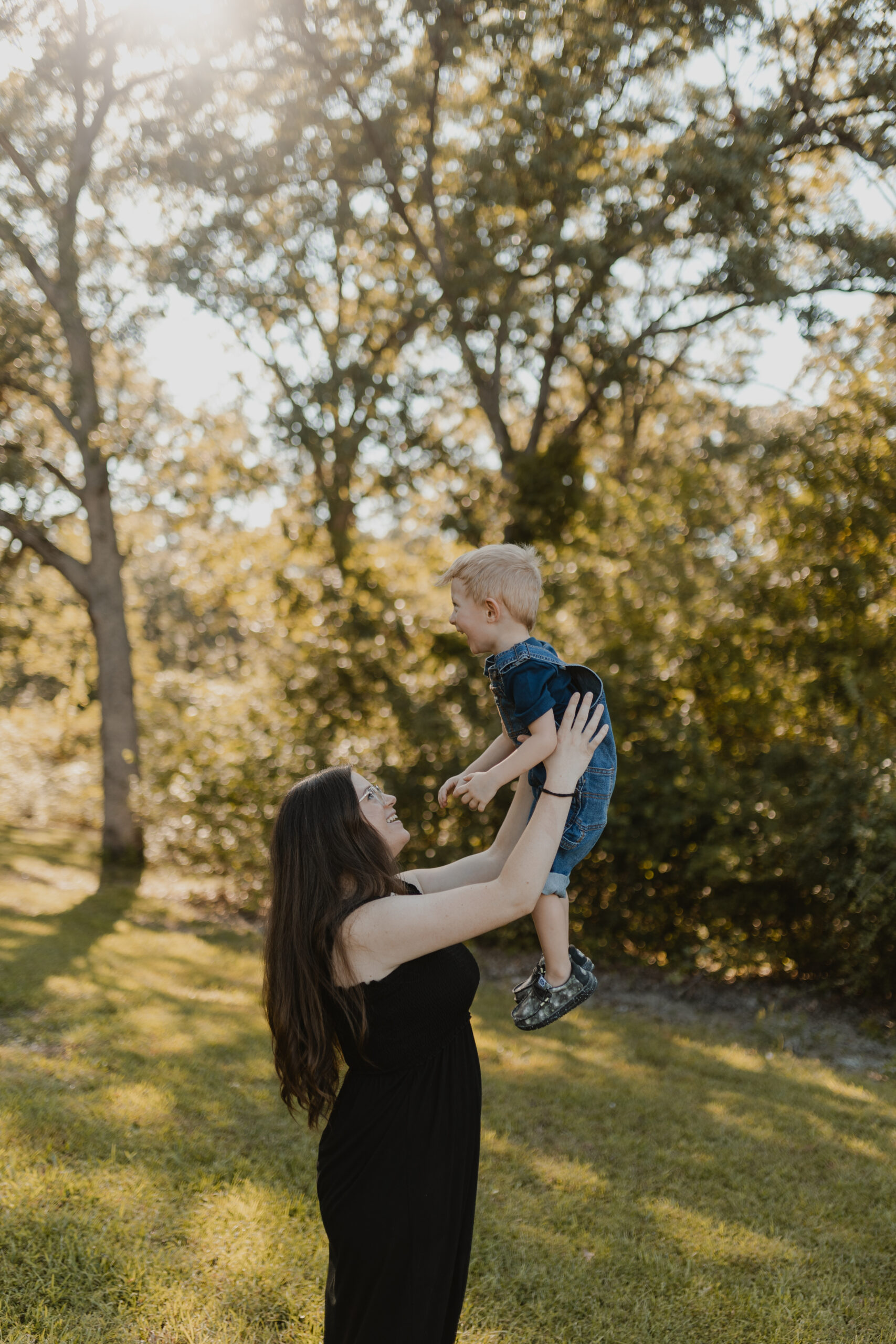 mom holding her son up and smiling at him while he laughs