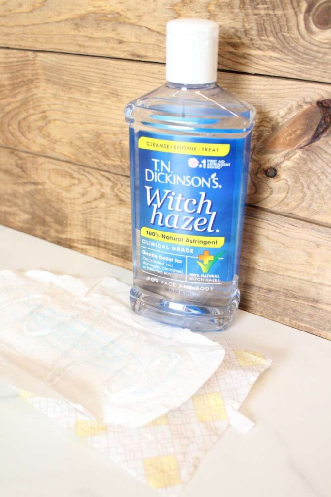 picture of a maxi pad opened with a bottle of witch hazel next to it.