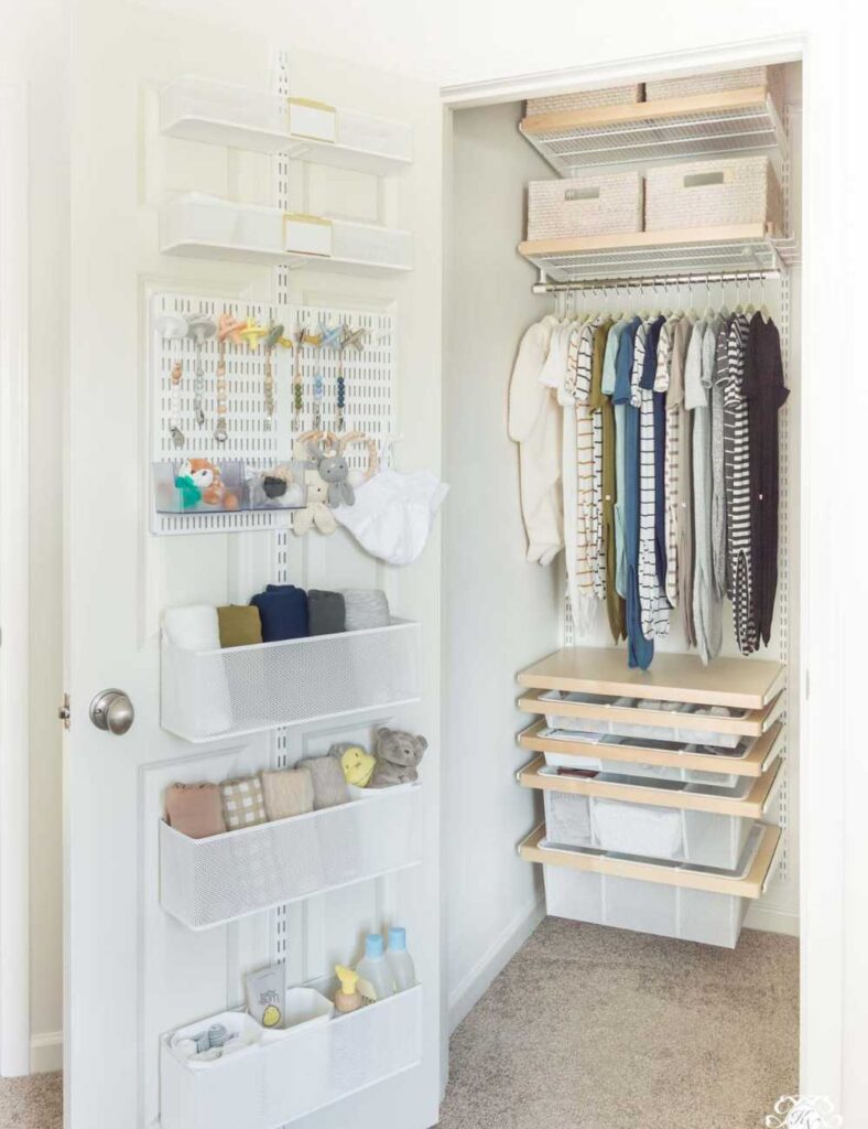 picture of a nursery closet with a full length organizer hanging on the door, metal wire drawer system at the bottom of closet, a clothing rod and shelf at the top with several outfits hanging up.