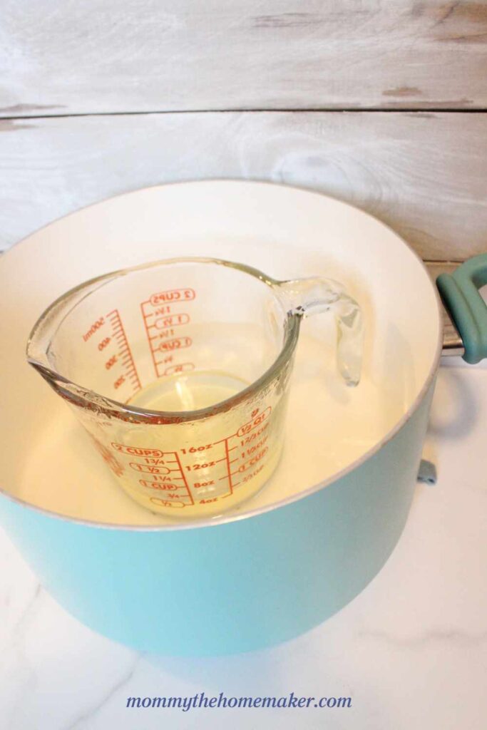 stock pot with water in it and a glass measuring cup with oil inside