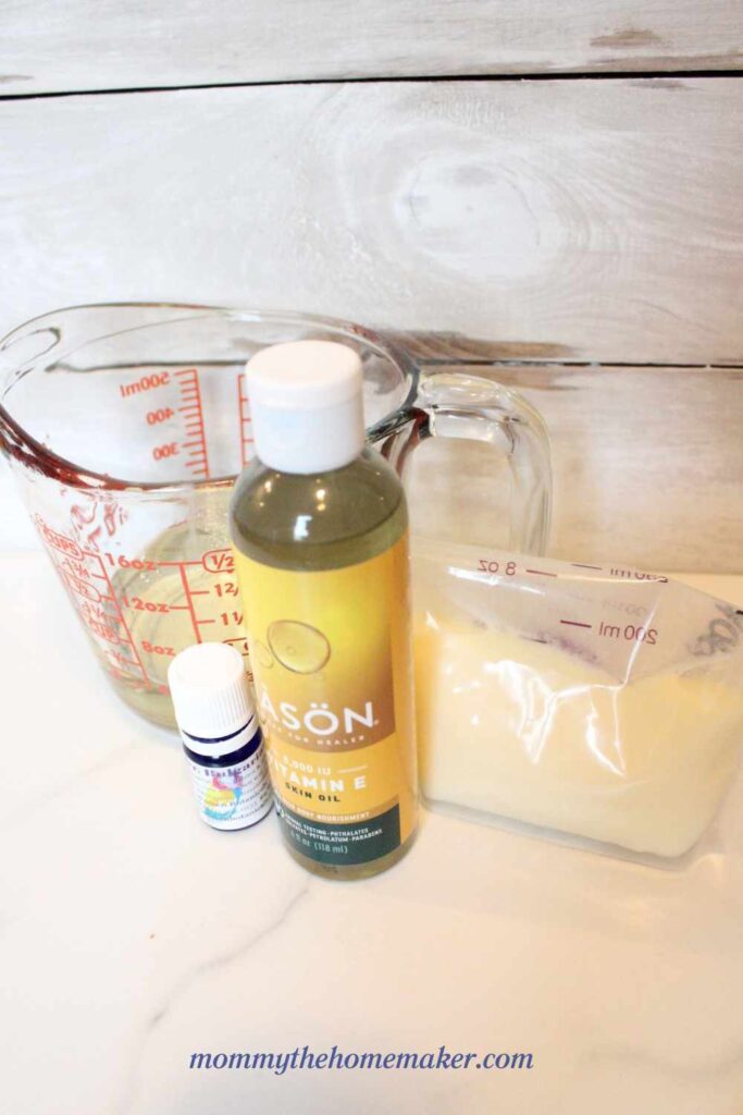 picture of vitamin e oil, bag of thawed breastmilk, essential oils, and a glass measuring cup